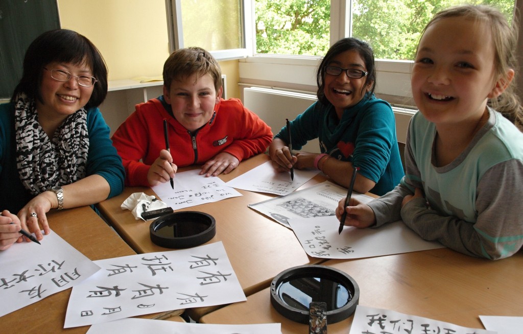 Aufgeweckte Sprachkünstler: Jennifer (von rechts), Jessy und Jan-Johann lernen bei ihrer Lehrerin Lidong Yang-Tonn neben dem gesprochenen Chinesisch auch die alte Kunst der Kalligrafie. Foto: Ulrike Havermeyer